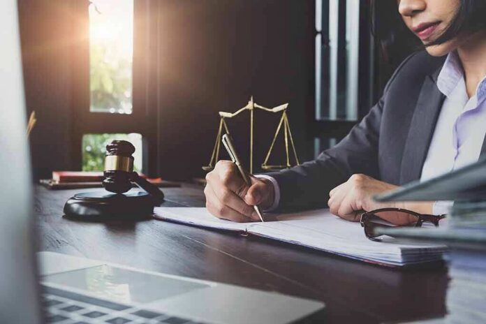 shutterstock_1135769117 Lawyer writing at desk with gavel and scales