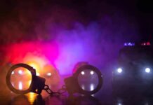Teen Arrest Stuns Fresno Nightlife Handcuffs on a surface with police cars and flashing lights in smoky darkness