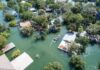 Life-Threatening Waves Slam Southern California Aerial view of flooded neighborhood with rescue boat navigating streets