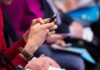 Conflict Shadows Rising State Senator Person in red sweater using a smartphone at an event
