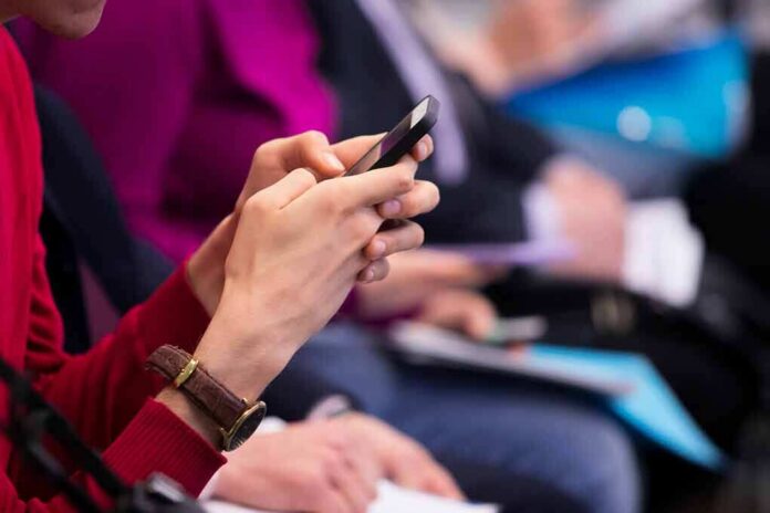 Person in red sweater using a smartphone at an event