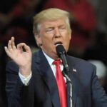 Trump Announces Massive Investment Donald Trump speaking at a rally with microphone and raised hand gesture
