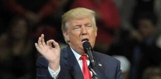 Donald Trump speaking at a rally with microphone and raised hand gesture