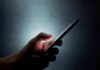 Kidnapping Hoax Explodes With AI Power Hand holding a smartphone in the dark