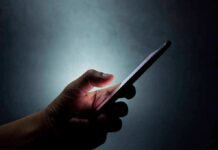 Kidnapping Hoax Explodes With AI Power Hand holding a smartphone in the dark