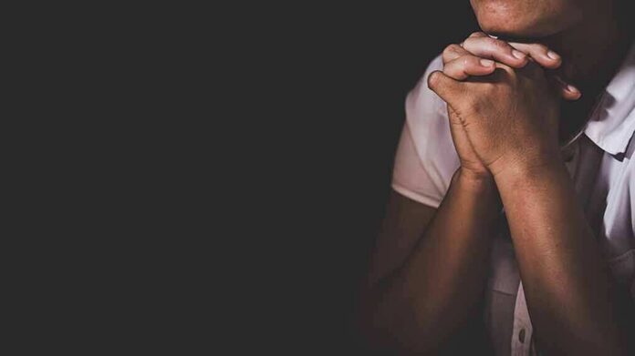 person with clasped hands in low light
