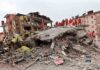Rescue workers in orange uniforms on a collapsed building site after an earthquake
