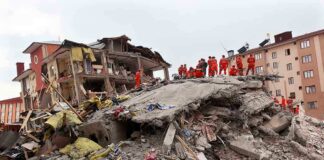 Rescue workers in orange uniforms on a collapsed building site after an earthquake