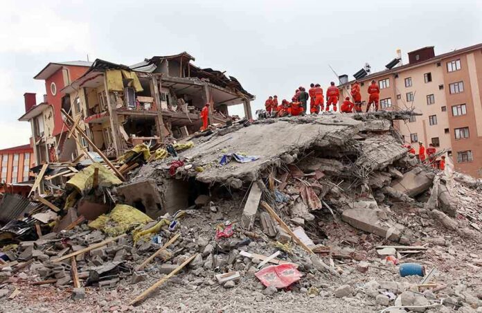 shutterstock_148947701 Rescue workers in orange uniforms on a collapsed building site after an earthquake