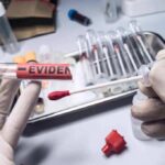 Gloved hands handling a swab and evidence tube