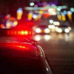 Stolen Service Gun Turns Night Into Hell Police car with flashing red lights on a city street at night