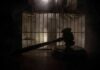Judge’s gavel in silhouette before prison bars
