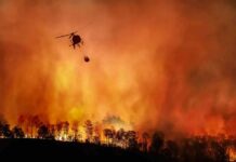 Wildfire Sparked By One Toss? Helicopter fights massive wildfire over burning forest