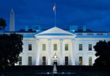 White House illuminated at dusk with flagpole and columns