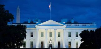White House illuminated at dusk with flagpole and columns