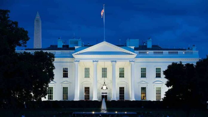 White House illuminated at dusk with flagpole and columns