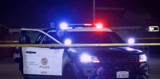 Police SUV with flashing lights at night behind yellow tape