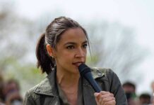 Lavish Lodging Storm Hits AOC AOC speaking into a handheld microphone outdoors