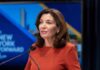 Kathy Hochul speaking at a podium with microphones