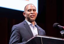 Hakeem Jeffries’ Nod Shows His True Colors Man in a suit speaking at a podium with a microphone