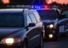 Road Rage Nightmare Shuts I-35 Police car with flashing lights behind a stopped vehicle at dusk