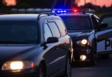 Police car with flashing lights behind a stopped vehicle at dusk