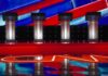 Epstein Firestorm Erupts In Georgia Debate stage with four empty podiums and bright red and blue backdrop