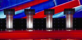 Debate stage with four empty podiums and bright red and blue backdrop