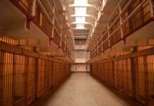 Prison cellblock corridor with barred cells and upper walkways