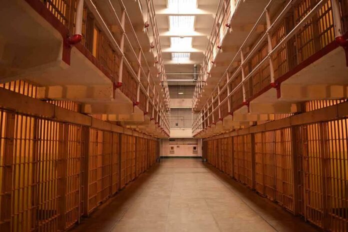 Prison cellblock corridor with barred cells and upper walkways
