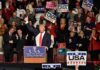 All-In Push – Stakes Explode In Midterms Donald Trump addresses a rally crowd at a podium, raising his fist