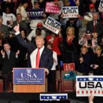 All-In Push – Stakes Explode In Midterms Donald Trump addresses a rally crowd at a podium, raising his fist