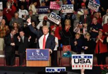 All-In Push – Stakes Explode In Midterms Donald Trump addresses a rally crowd at a podium, raising his fist