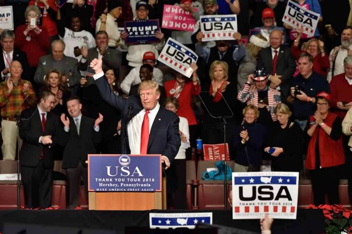 Donald Trump addresses a rally crowd at a podium, raising his fist