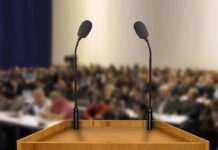Podium with two microphones facing a blurred audience